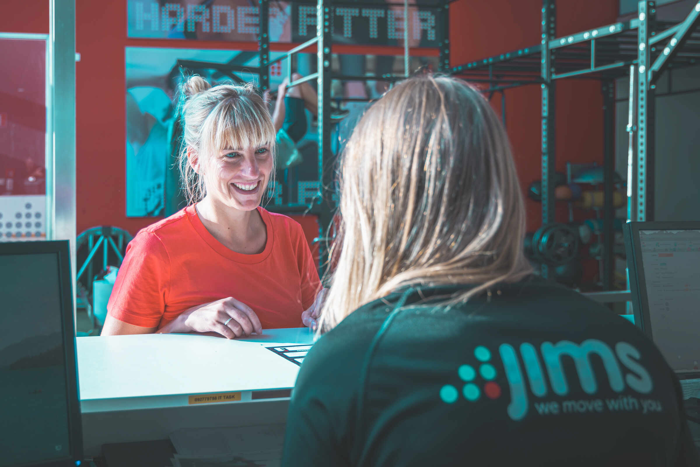 Une femme sourit à son coach pendant son entraînement chez Jims Fitness.