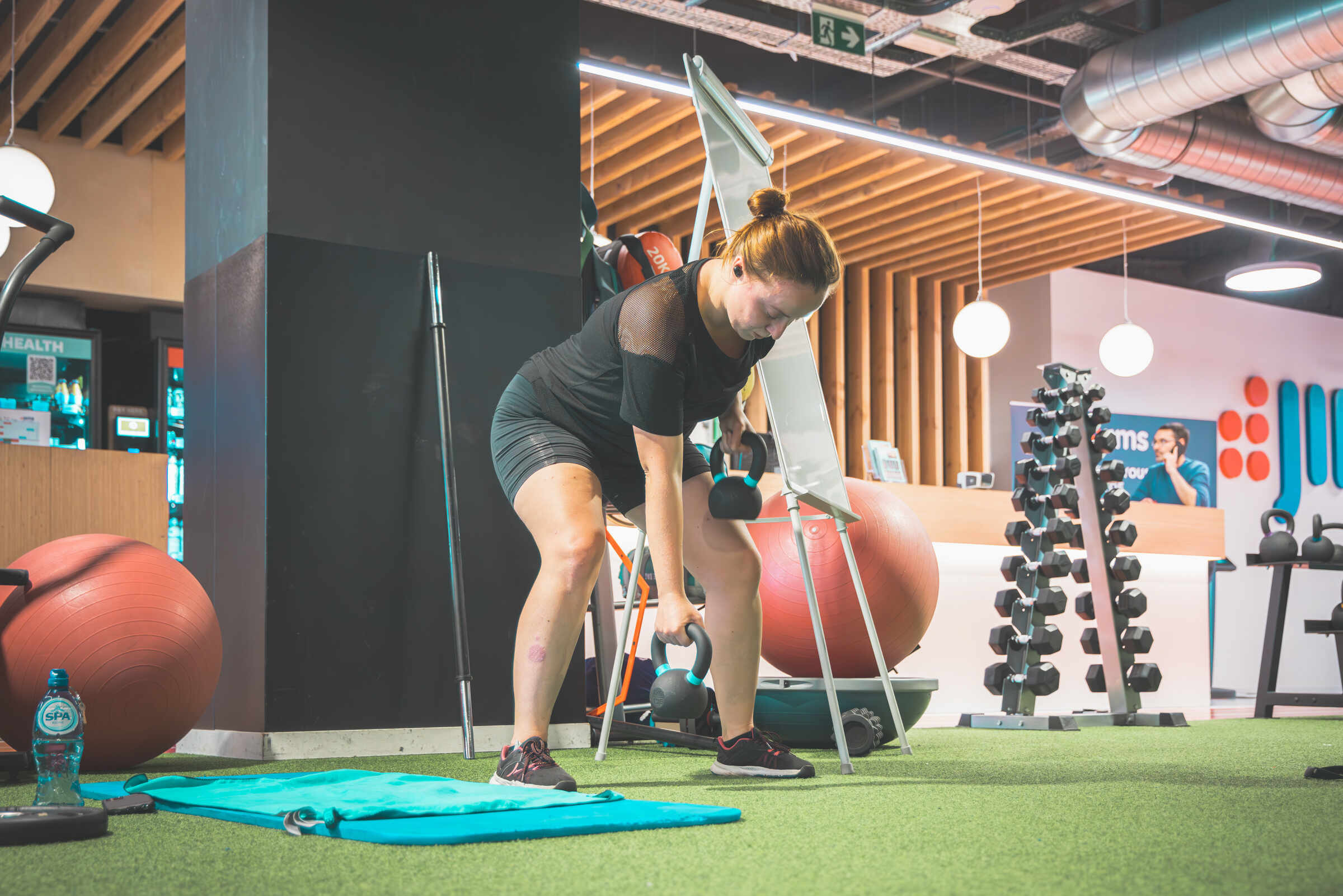 Vrouw doet een kettlebell-oefening tijdens krachttraining bij Jims Fitness
